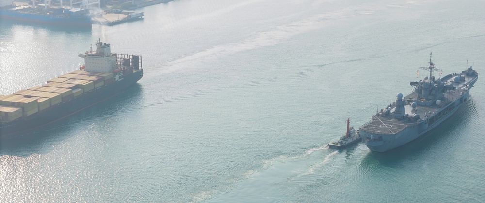 U.s.,Navy,Warship,And,A,Massive,Container,Ship,Maneuvering,In